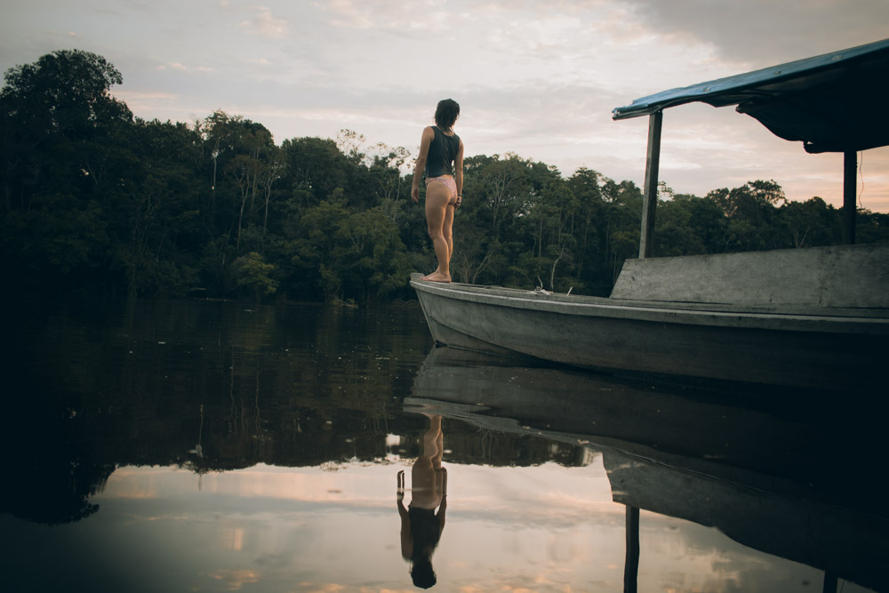 Ana na ponta de um barco de madeira a ver o por do sol no Rio Amazonas