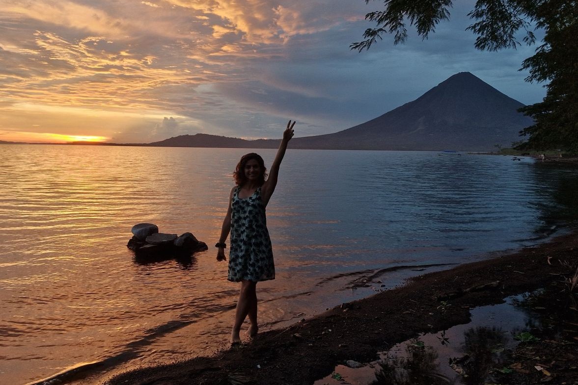 Ana em frente a paisagem em Ometepe, na Nicarágua, com vulcão e por do sol ao fundo