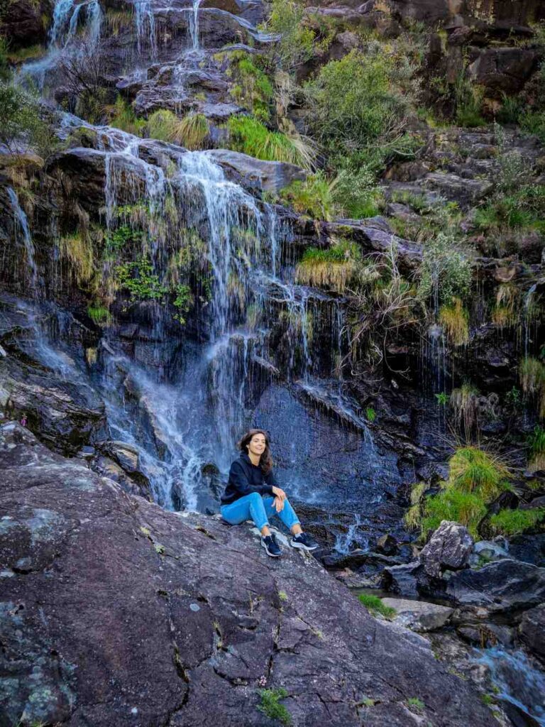 Pessoa sentada em frente a uma cascata