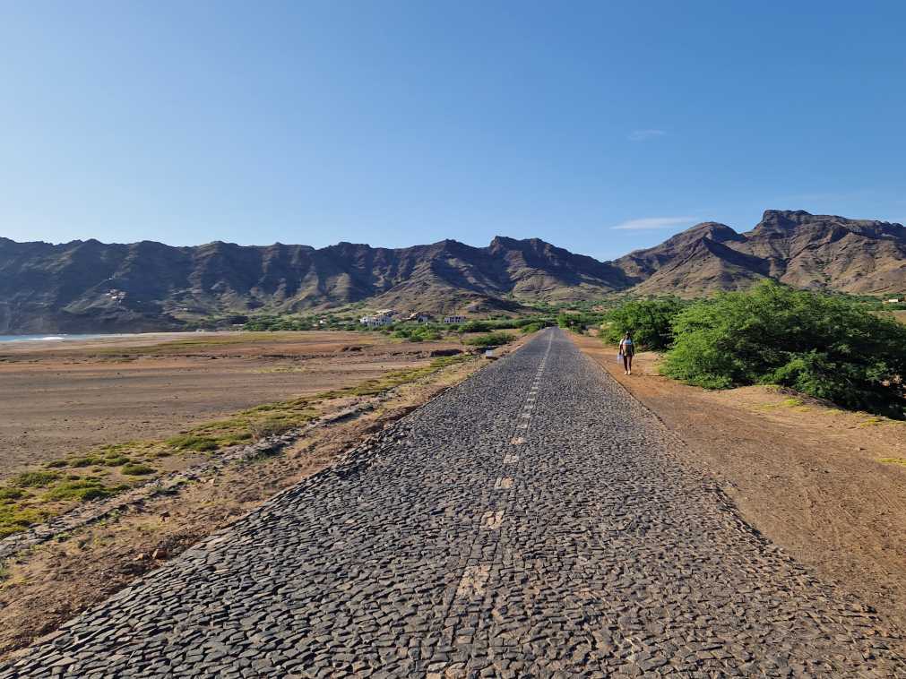 Estrada longa em pedra com terra batida e vegetação nas margens em São Vicente