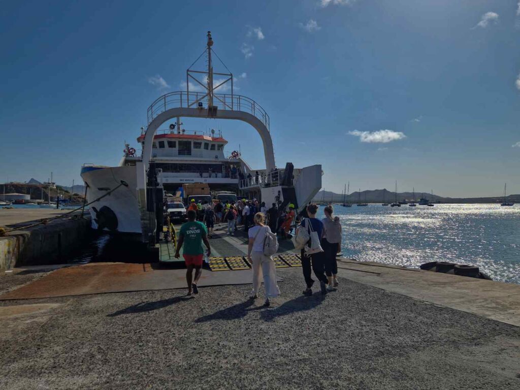 Pessoas a entrara para o ferry em São Vicente, Cabo Verde, com o mar a brilhar à esquerda