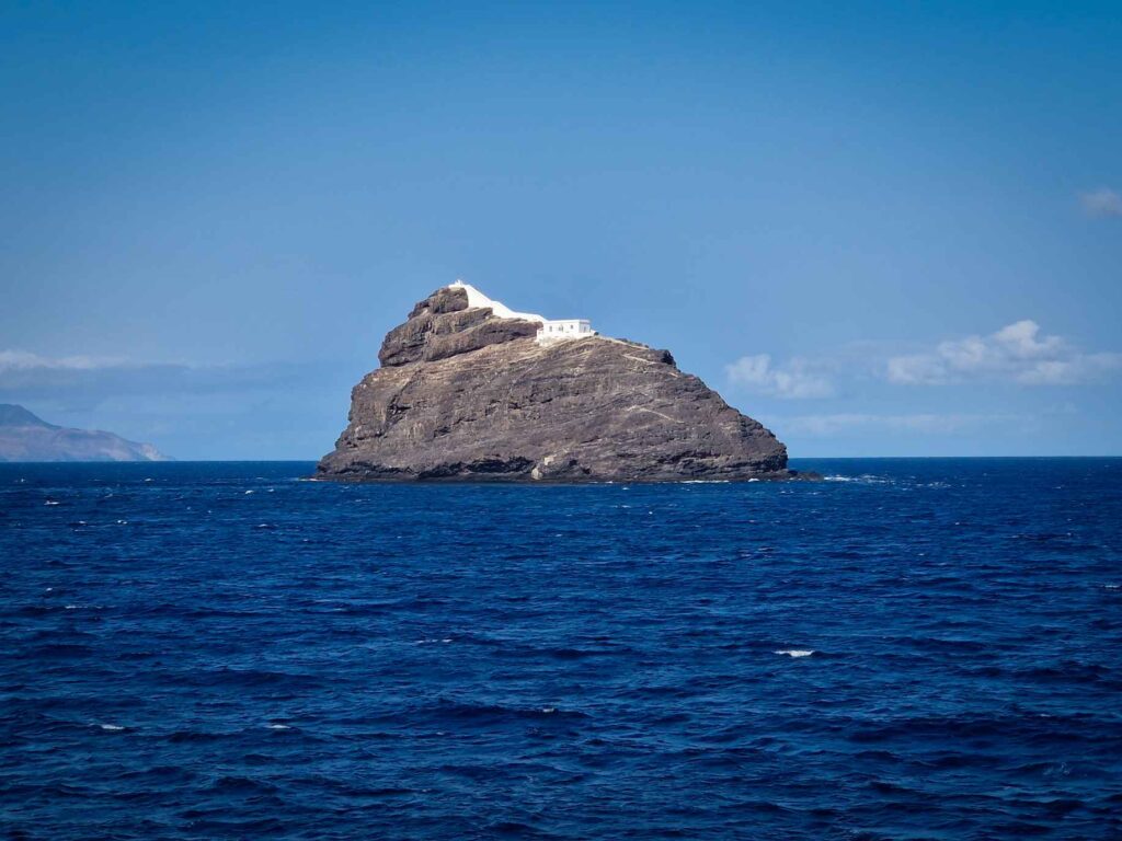 Ilhéu com edifício branco no topo, no meio do mar azul marinho