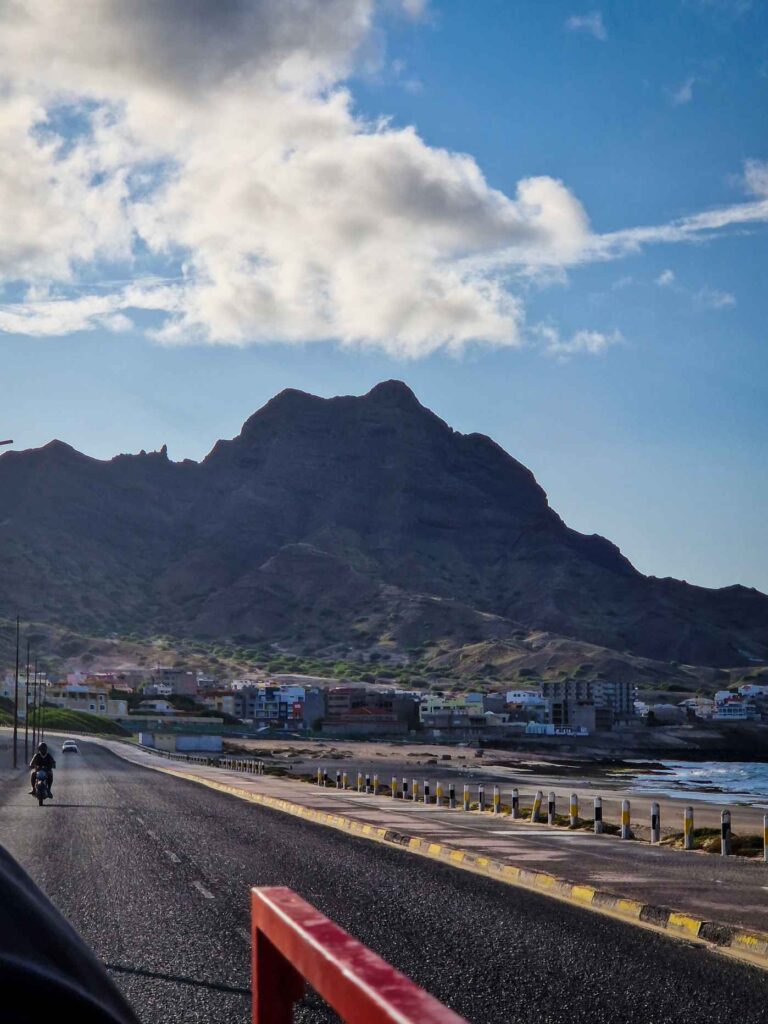 Vista para o monte com formato de cara em São Vicente, desde uma estrada com uma moto e um carro