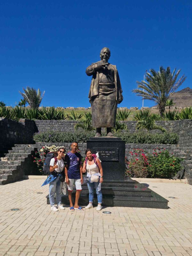 Três pessoas em frente a uma estátua, no Aeroporto Cesária Évora em São Vicente