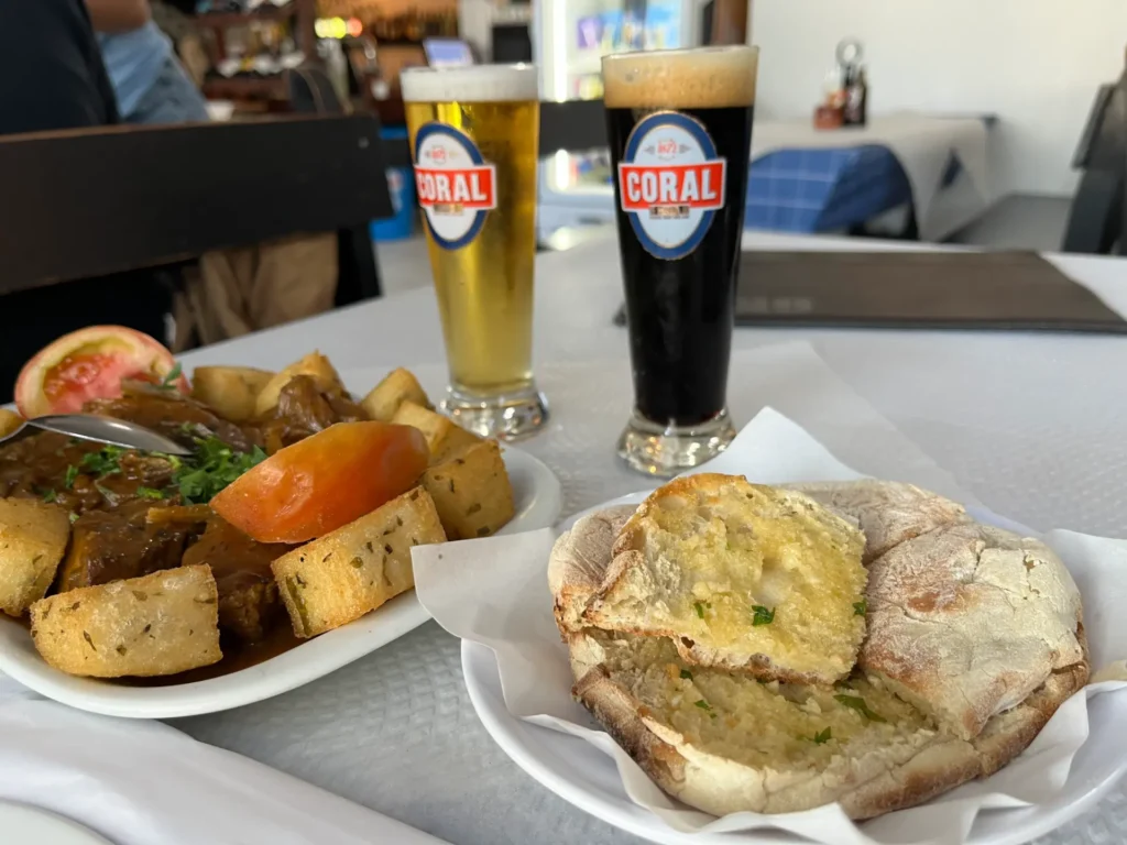 Prato de bolo do caco e prato de mandioca frita com duas cervejas Coral