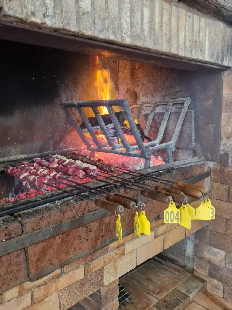 Várias espetadas de carnes a assar numa fogueira