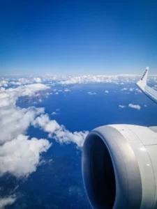 Vista desde o avião sobre o céu e o mar azuis, com algumas nuvens brancas