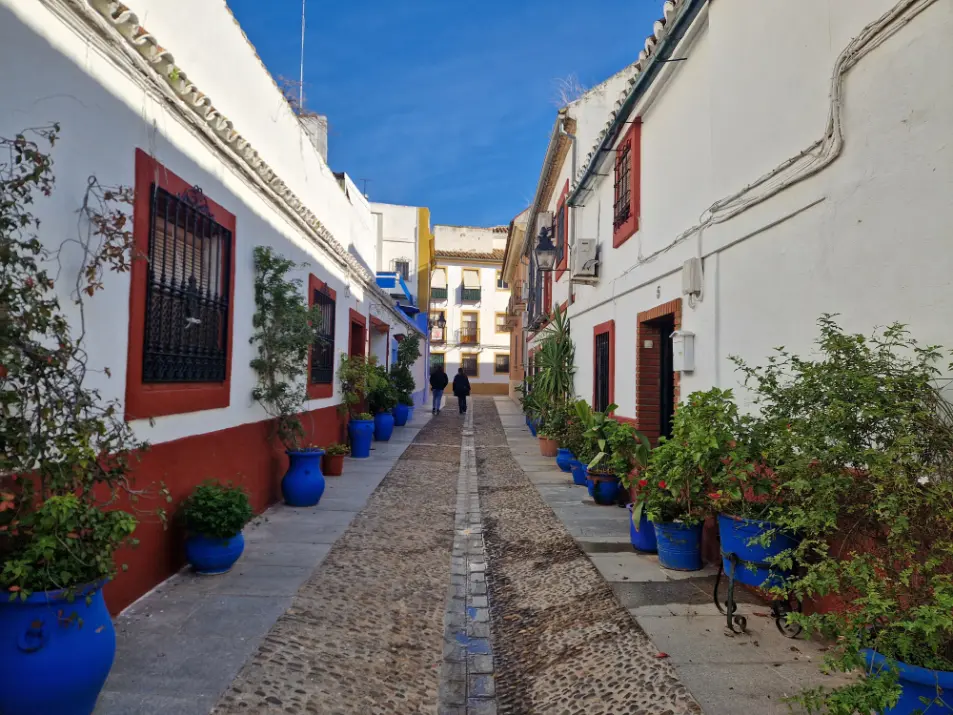 Rua do bairro de San Basilio com vasos azuis e casas brancas e vermelhas