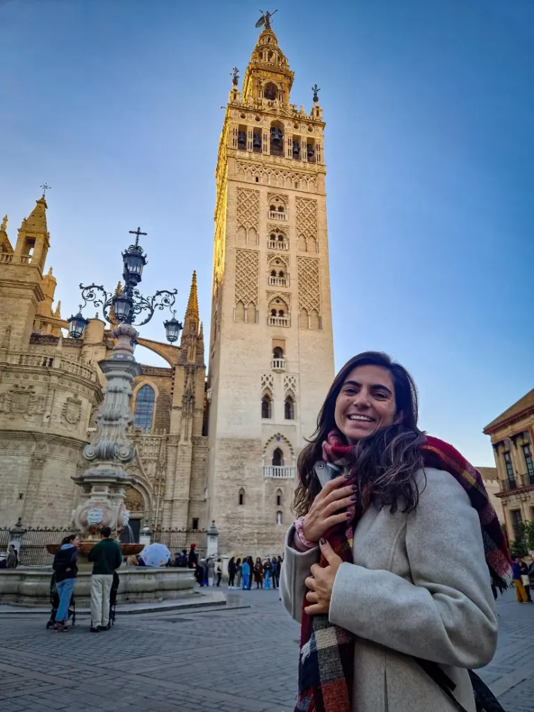 Pessoa a sorrir em frente à Giralda, a torre principal da Catedral de Sevilha