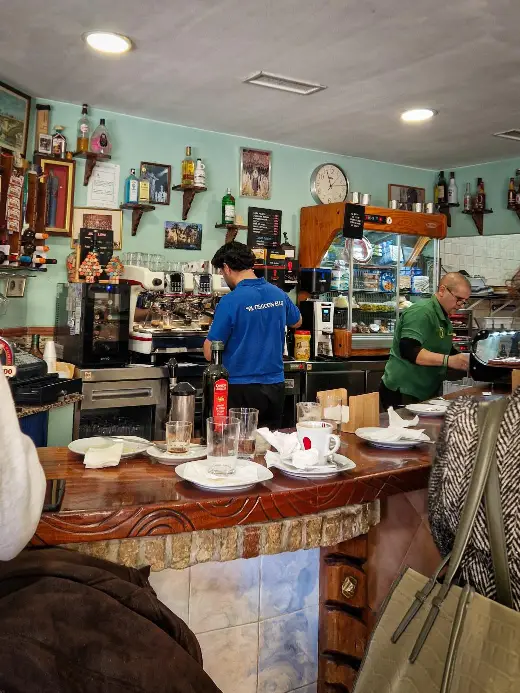 Balcão do Bar El Candelária em Sevilha com louça suja e pessoas a trabalhar
