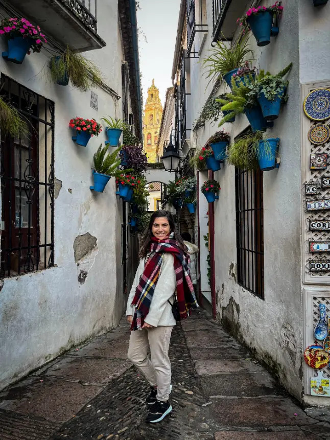 Pessoa em rua estreita de paredes brancas decoradas com vasos azuis