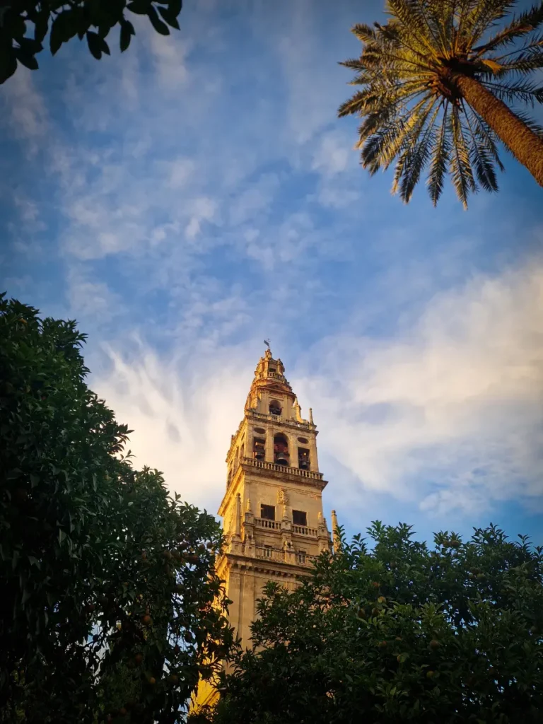 Torre da Mesquita-Catedral de Córdova com as copas de algumas árvores e um céu azul ao fundo
